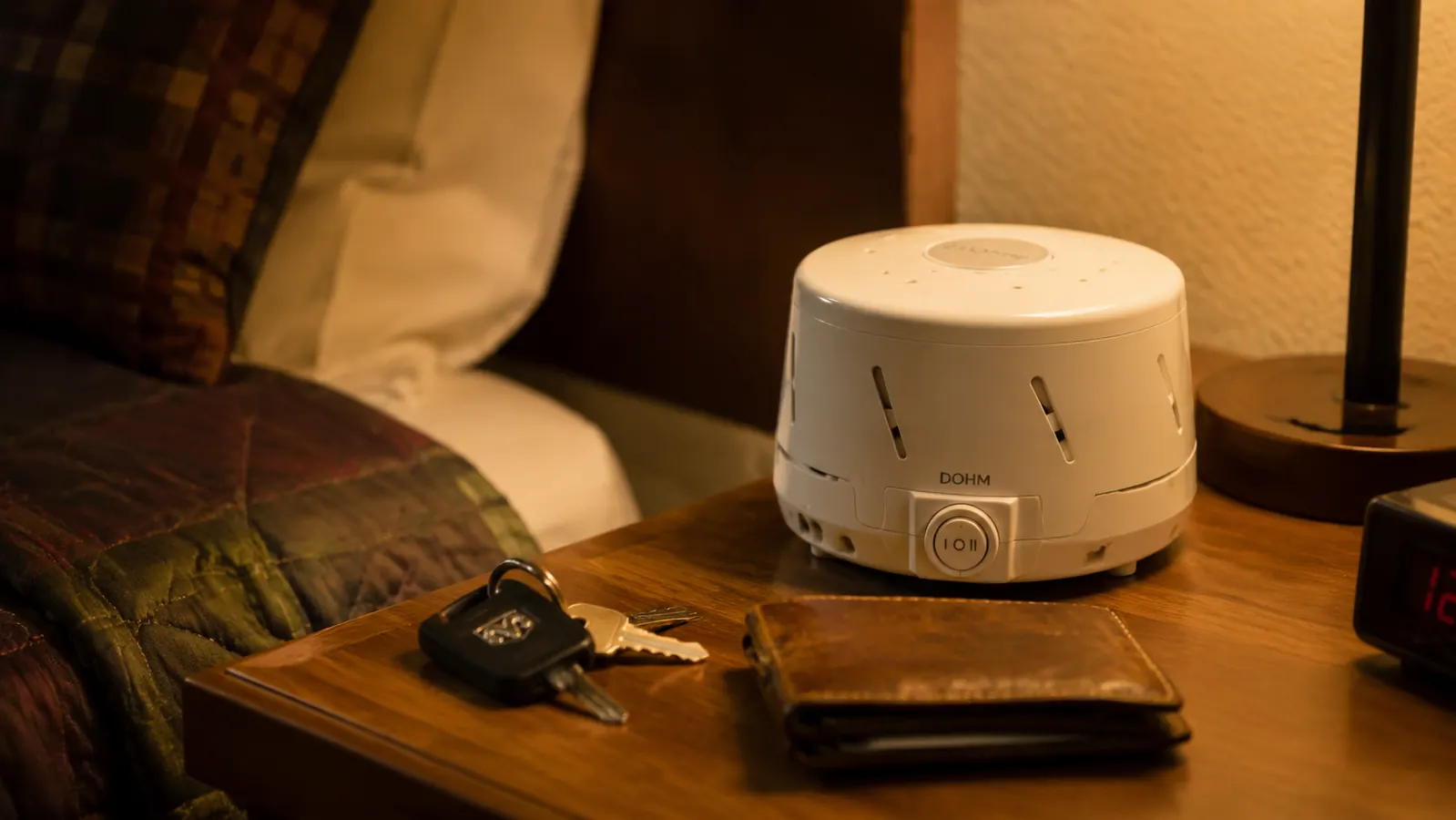Yogasleep Dohm Classic white noise machine on a motel nightstand next to a trucker's keys and phone